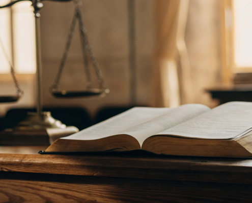 A business litigation lawyer's desk with scales of justice and an open law book.