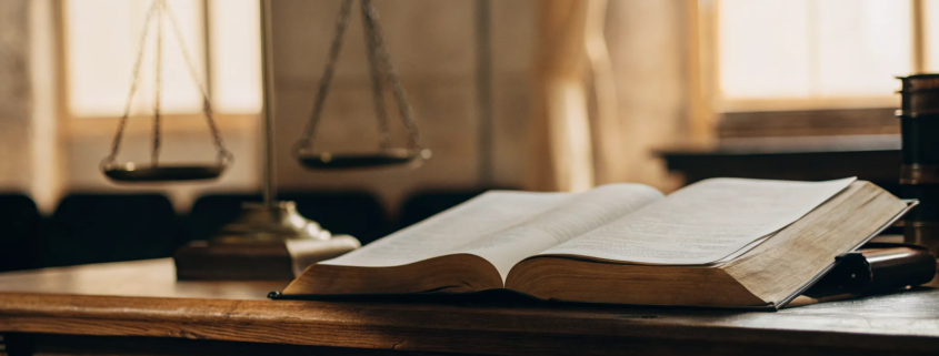 A business litigation lawyer's desk with scales of justice and an open law book.