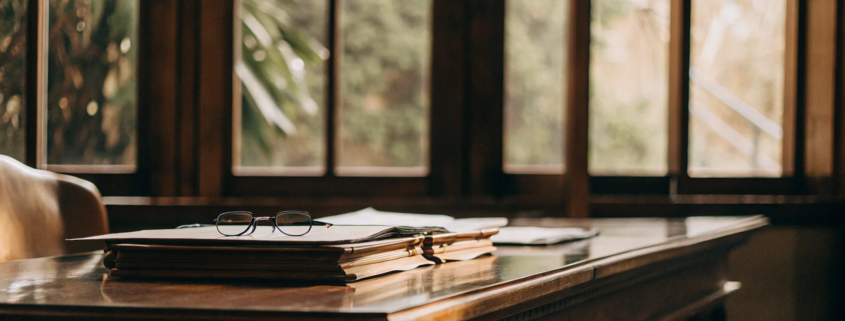 A lawyer's desk with documents and glasses for a will contest case.