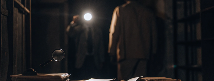 Investigators use a flashlight and magnifying glass on documents to see what constitutes business fraud.