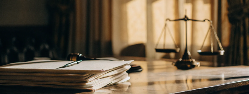 Gavel and scales of justice on a desk with papers about the cost to contest a will.