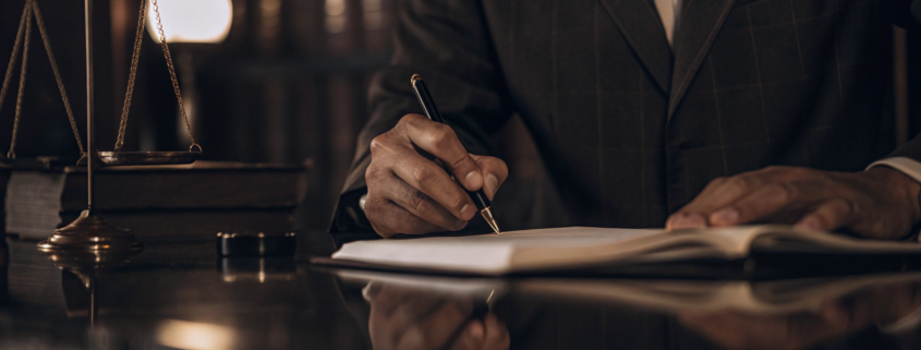 An oral contract breach attorney works on a case with scales of justice and law books on the desk.