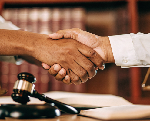 A shareholder shakes hands with an attorney to resolve a business dispute through litigation.