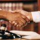 A shareholder shakes hands with an attorney to resolve a business dispute through litigation.