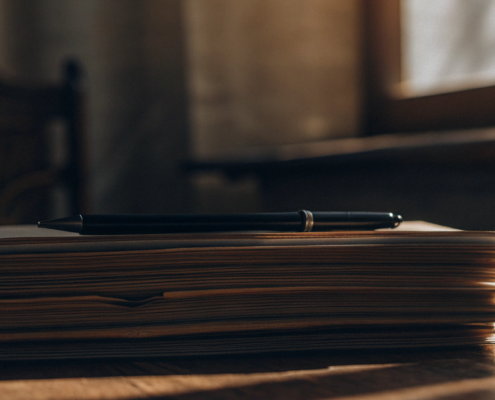 A stack of contracts with a pen, ready for a lawyer review to determine the cost.