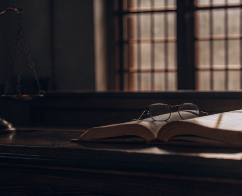 Open law book and glasses on a courtroom desk to determine the cost of a quiet title action.