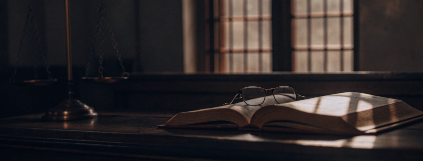 Open law book and glasses on a courtroom desk to determine the cost of a quiet title action.