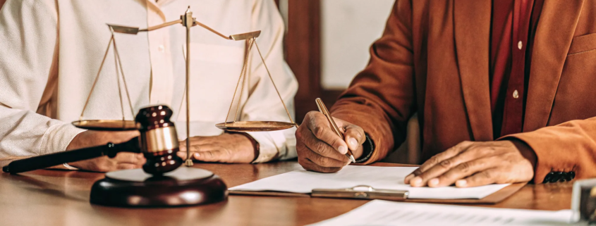 A lawyer explains the cost of a partition lawsuit to a client with a gavel and documents on the desk.